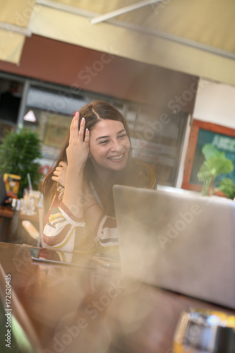 Young woman sitting in cafe and watching on laptop.
