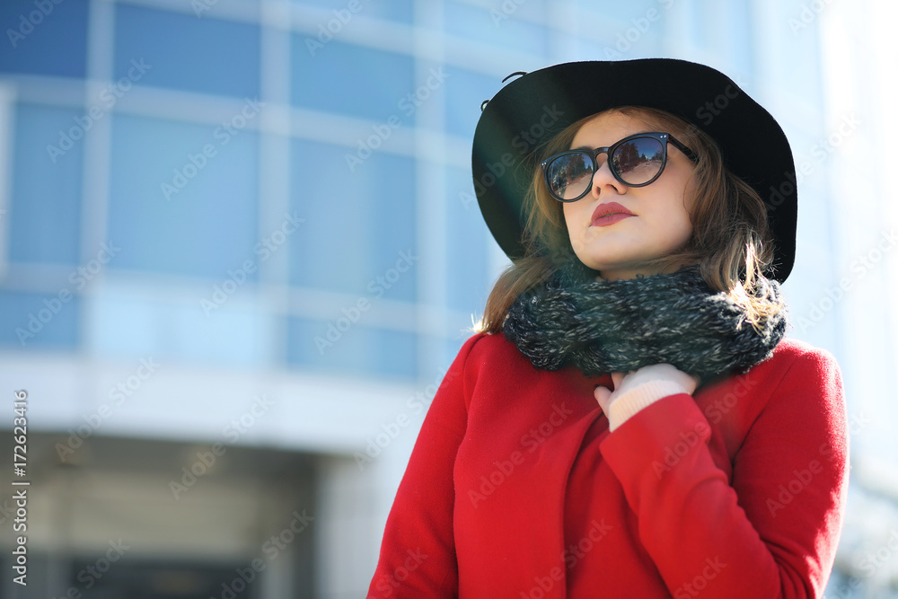 Cute businesswoman in a red coat against a background of glass Cute businesswoman in a red coat against a background of glass