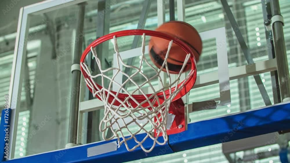A student is shooting for the basketball hoop and he almost misses it. Kids are playing basketball in a school gym. A student is shooting for the basketball hoop and he almost misses it. Kids are playing basketball in a school gym.
