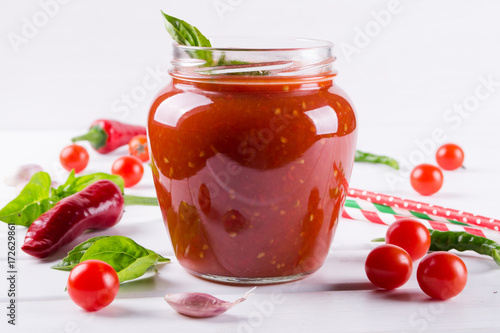 Spicy sweet tomato sauce with garlic, pepper and herbs in a glass jars.