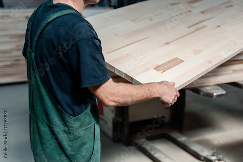 Man worker holding a big countertop in a furniture manufacture production.