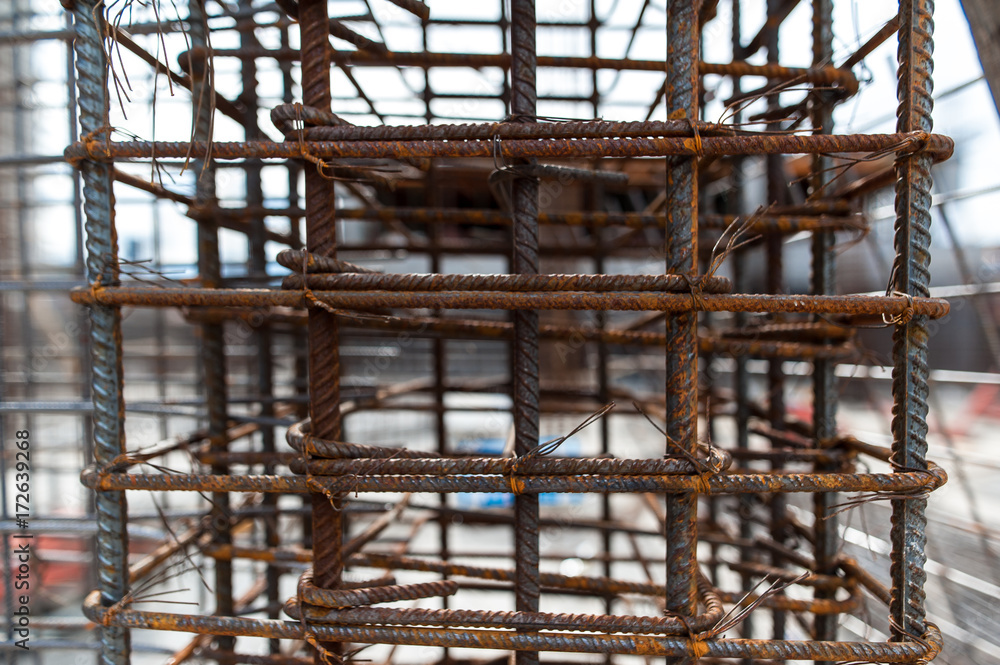 Reinforcement net of concrete in the construction site, metal rods for strength with a building under construction on the background