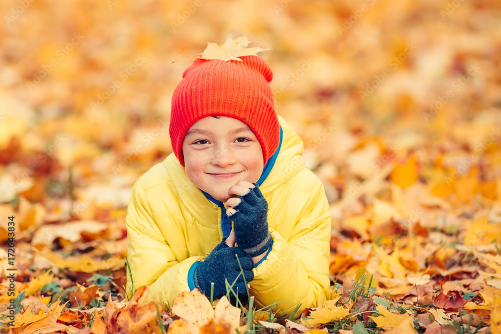 Smiling boy lying on the yellow leaves in autumn park Smiling boy lying on the yellow leaves in autumn park