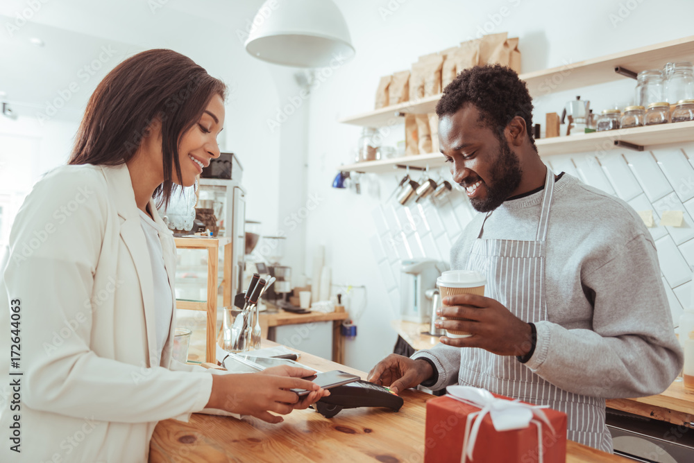 Fototapeta premium Female customer using phone to pay for order in cafe