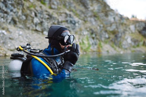 Male diver in wetsuit checking equipments before immerse