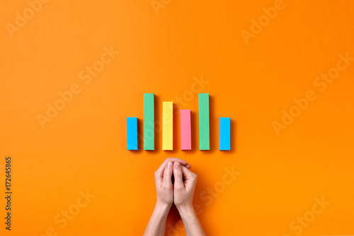Hands on orange desk with colorful bar charts