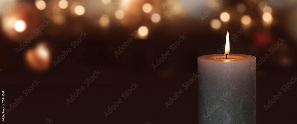 Burning candle with golden bokeh