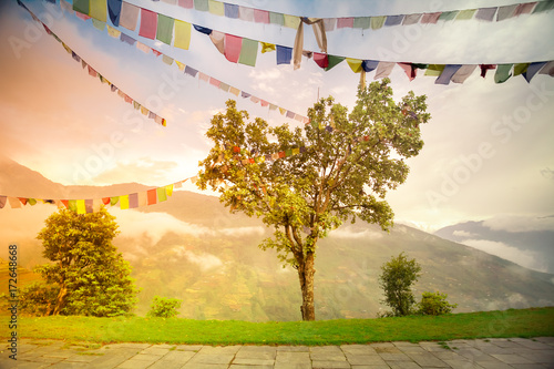 Buddhist tibetan prayer flags against blue cloudy sky. Many colorful waving flags suspended between trees. Himalayas mountain landscape. Trekking in Nepal. Holiday, travel, sport, recreation