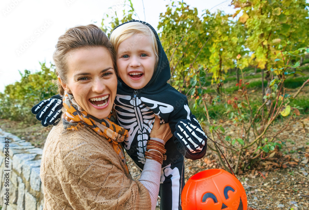 Obraz premium smiling modern mother and daughter on Halloween outdoors