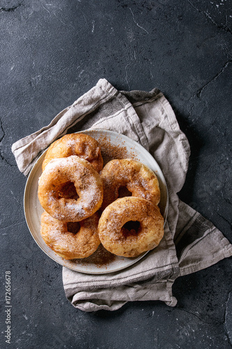 Photography Plate of homemade donuts with sugar and cinnamon powder on gray textile napkin over dark texture background