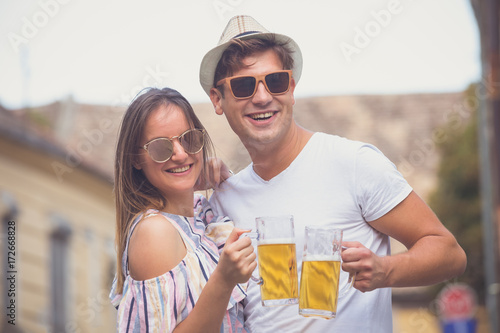 Portrait of beautiful couple toasting with beer outdoor