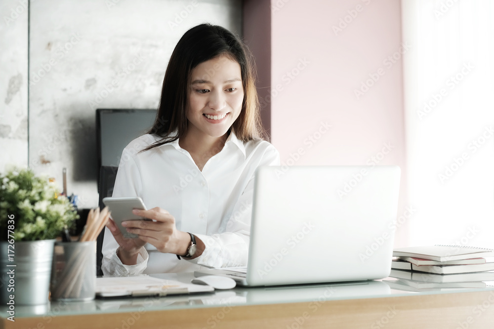 Young businesswoman using smart phone while working at her office desk background, business people and communication concept, office lifestyle Young businesswoman using smart phone while working at her office desk background, business people and communication concept, office lifestyle
