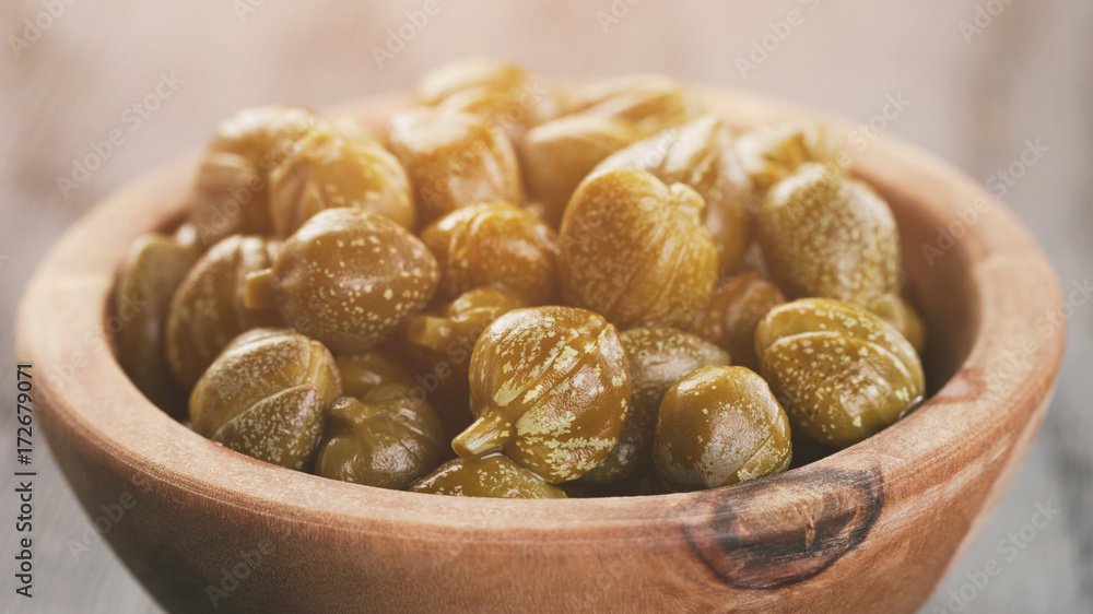 marinated capers in olive bowl on wood table marinated capers in olive bowl on wood table