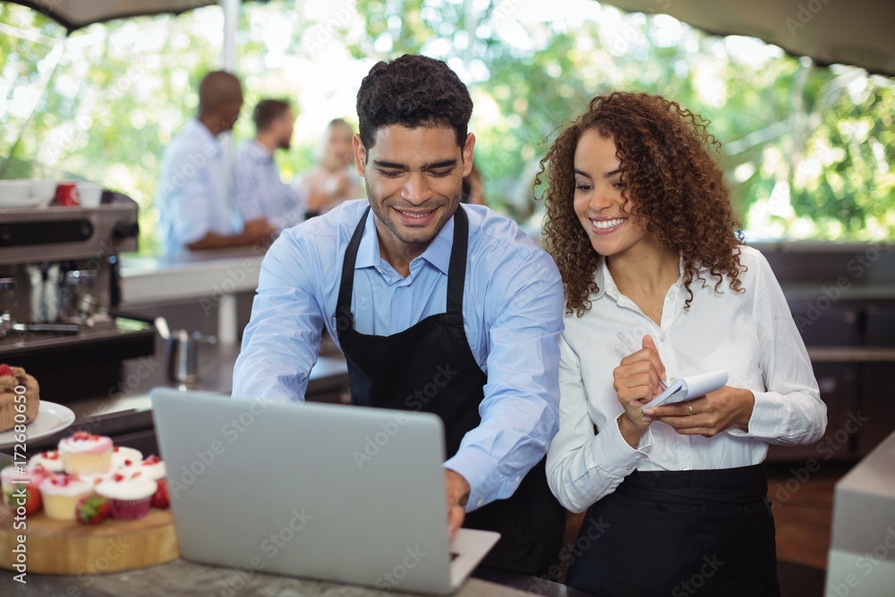 Male waiter and female waitress with laptop Male waiter and female waitress with laptop