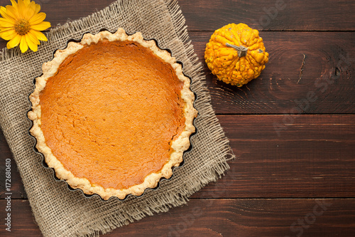pumpkin homemade pie at wooden background arranged with food ingredients top view