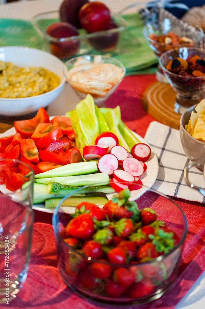 Table served with fruits and vegetable dishes. Bowl with hummus, eggplant salad, bread, vegetables, fruits, lemonade bottles. Top view. Dinner party