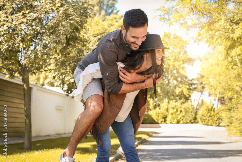 Young coupe in city park. Girlfriend carrying her boyfriend on piggyback.  Stock Photo | Adobe Stock
