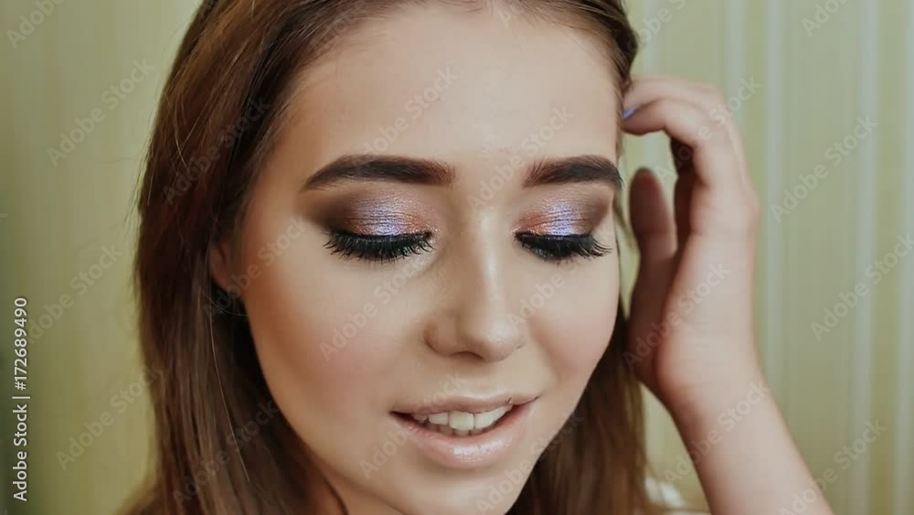 The girl demonstrates her delicious makeup. Close up portrait of young beautiful woman with long brunette curly hair posing against architectural background and looking at you. Professional Make-up The girl demonstrates her delicious makeup. Close up portrait of young beautiful woman with long brunette curly hair posing against architectural background and looking at you. Professional Make-up