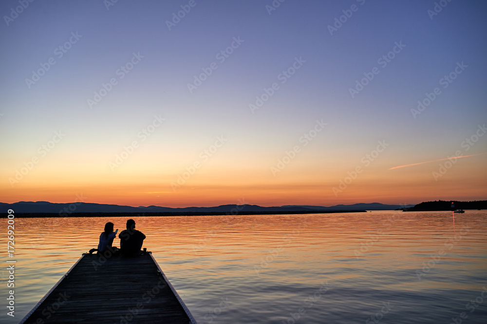 Couple on a pier at sunset silhouette