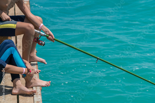 Children are fishing on the pier. Close-up of hands and rods