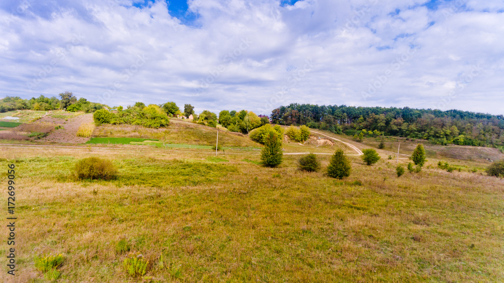 Fototapeta premium Aerial view of the landscape: hills, trees and blue sky with white clouds.