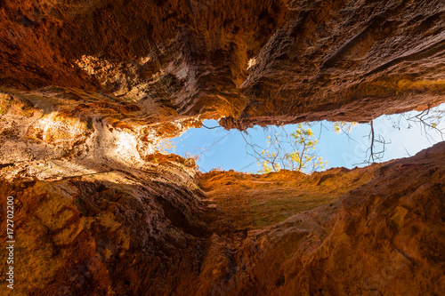 Crevice in the red loamy wall of Providence Canyon bottom view in sunny day, USA
