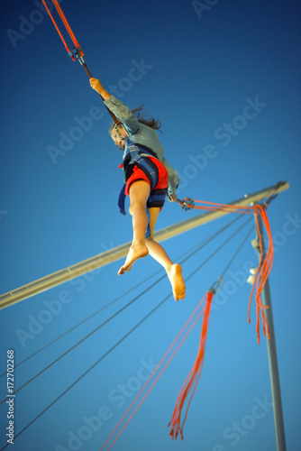 Obraz na plátně Little girl on bungee trampoline with cords