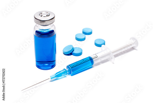 A syringe with blue vaccine and pills