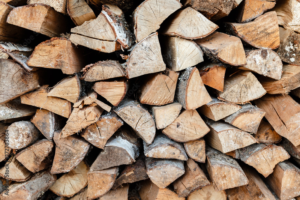 Firewood stacked in a woodpile on wooden background. Background of firewood stack. Firewood stacked in a woodpile on wooden background. Background of firewood stack.