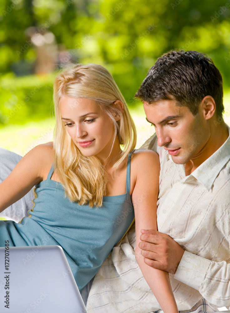 Young couple working with laptop, outdoor Young couple working with laptop, outdoor