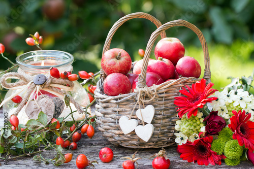 Herbstdekoration mit Äpfel im Weidenkorb,Herbstblumen und Hagebutten als Kartenmotiv