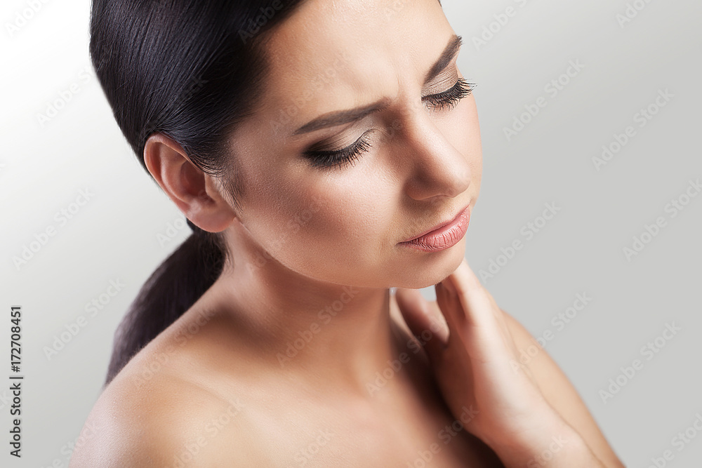 A brunette patient with an influenza disease has a throat, close-up, isolated on a gray background. Beautiful girl, sore throat, flu, cold, health concept.