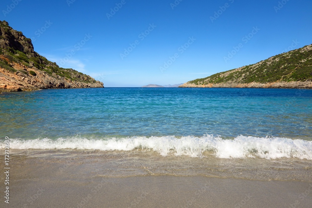 Blue sea cove with gentle surf breaking on beach. Solitude, escape, relaxation concept with copy space
