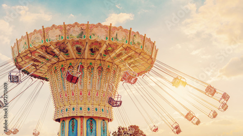 carousel ride spins fast in the air at sunset - vintage filter effects - a swinging carousel fair ride at dusk photo