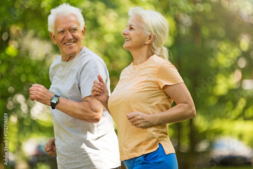 Senior couple running in park 