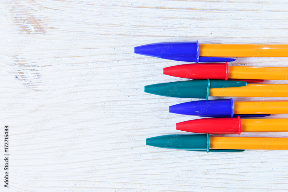 Obraz premium Colorful pens on white wooden background