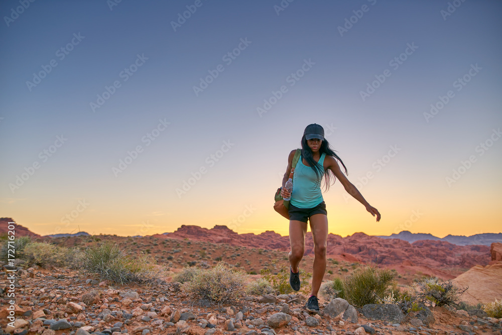female african american hiker walking throguh desert at sunset