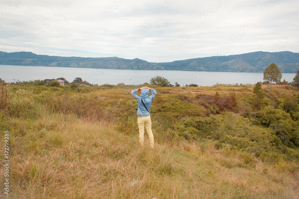 woman standing on hill looking at the lake toba