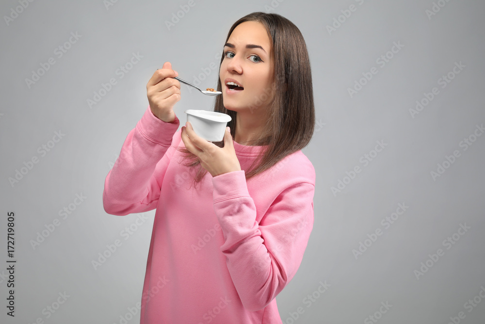 Young woman eating yogurt on light background Young woman eating yogurt on light background