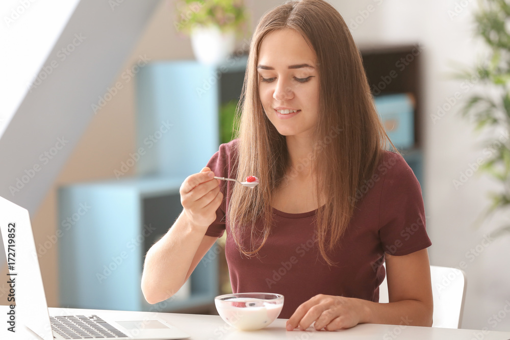 Young woman eating yogurt at table Young woman eating yogurt at table