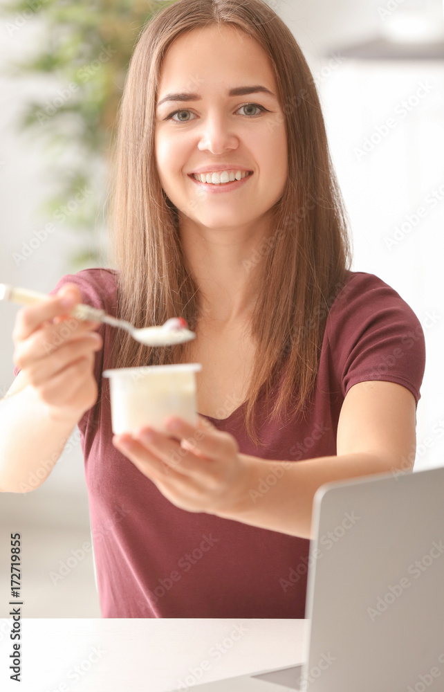 Young woman eating yogurt at table Young woman eating yogurt at table