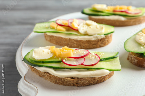 Tasty sandwiches with fresh cucumber on wooden board
