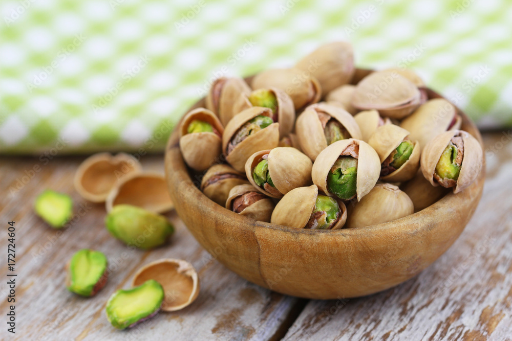 Pistachio nuts in bamboo mat on rustic wooden surface, closeup