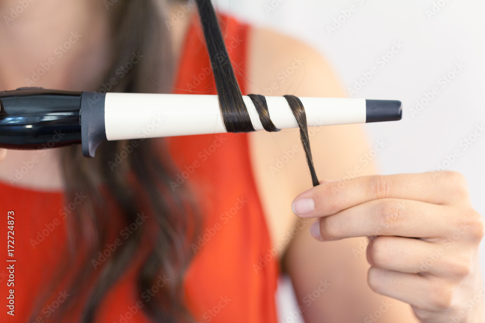 Naklejka premium Hairstylist curling hair client in hairdressing salon