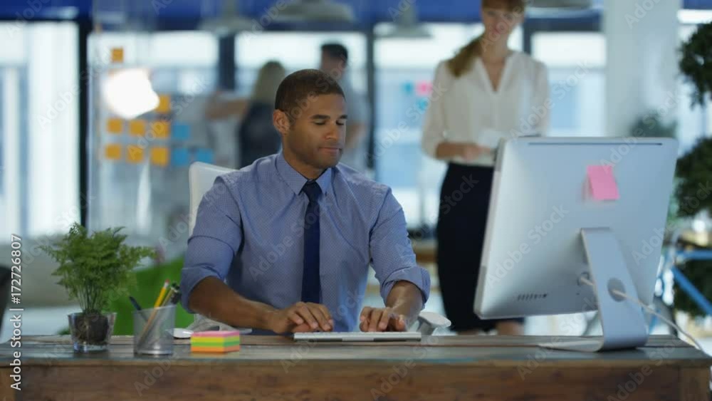 Man working at his desk in modern office and talking to female colleague. Man working at his desk in modern office and talking to female colleague.