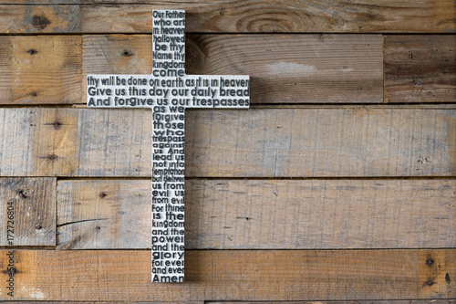 White wooden cross with the Lord's prayer on the shabby  natural wooden  plank.