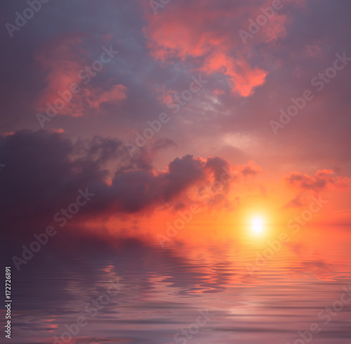 Storm clouds against the background of a blood-red sunset and a calm sea.