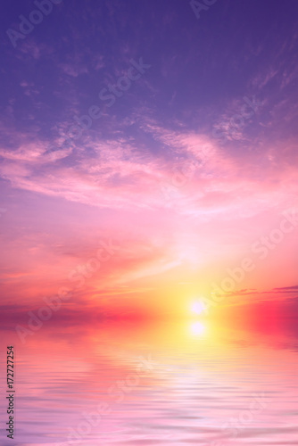 A purple sunset with a large sun with a small amount of clouds over the sea. © Sviatoslav Khomiakov