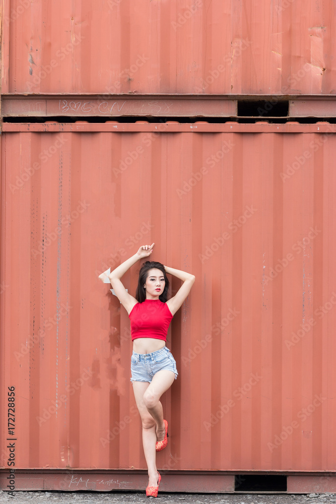 Portrait of fashion pretty hot girl wearing a red shirt at outdoors,Containers are the background. Portrait of fashion pretty hot girl wearing a red shirt at outdoors,Containers are the background.