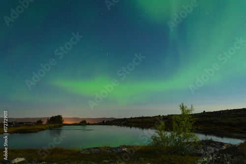 Autumn Aurora, the polar lights in the sky over the river,lake and hills at night . © Moroshka